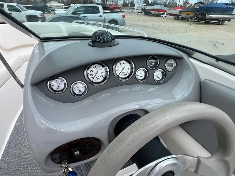 Slide: The Image of 2004 Chaparral 210 SSi boat dashboard with gauges and compass, parked in a marina. - 23