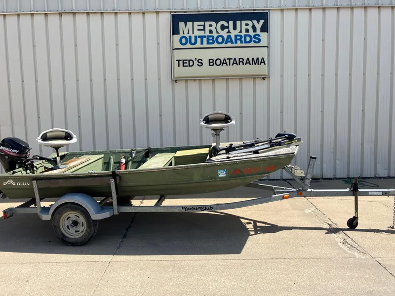 Slide: The Image of 1990 Alumacraft 14' Jon boat on trailer at Ted's Boatarama, Mercury Outboards sign visible. - 2