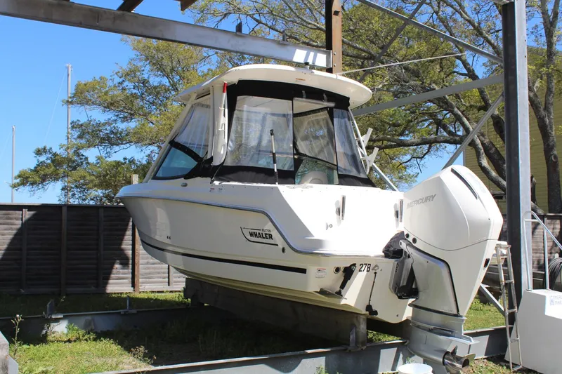 Slide: The Image of 2021 Boston Whaler 240 Vantage boat on lift, surrounded by trees and fencing. - 14