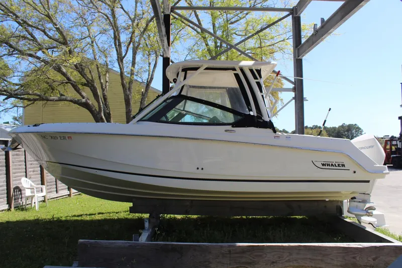 Slide: The Image of 2021 Boston Whaler 240 Vantage boat on a lift, surrounded by trees and a building. - 15