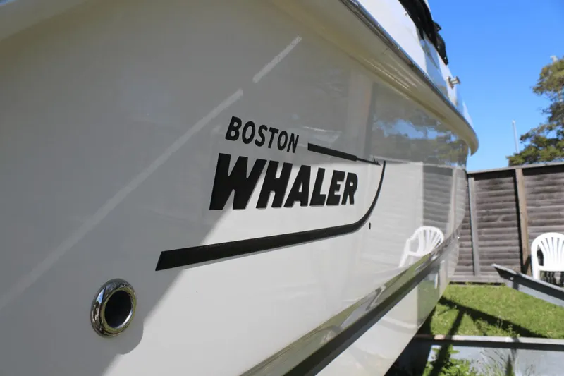 Slide: The Image of 2021 Boston Whaler 240 Vantage boat side view with logo, outdoors. - 16