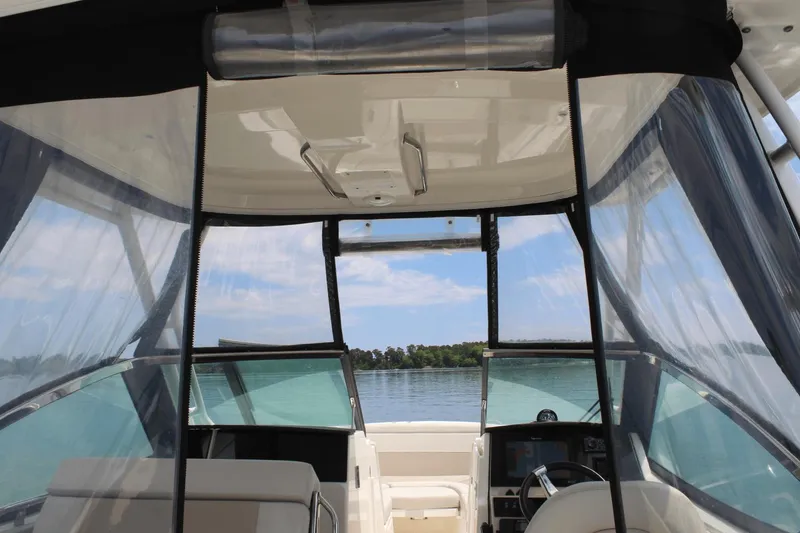 Slide: The Image of Interior view of 2021 Boston Whaler 240 Vantage boat with clear canopy and scenic water backdrop. - 26