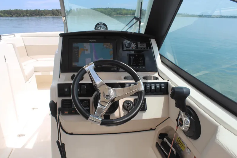Slide: The Image of 2021 Boston Whaler 240 Vantage helm with steering wheel, controls, and navigation display. - 28