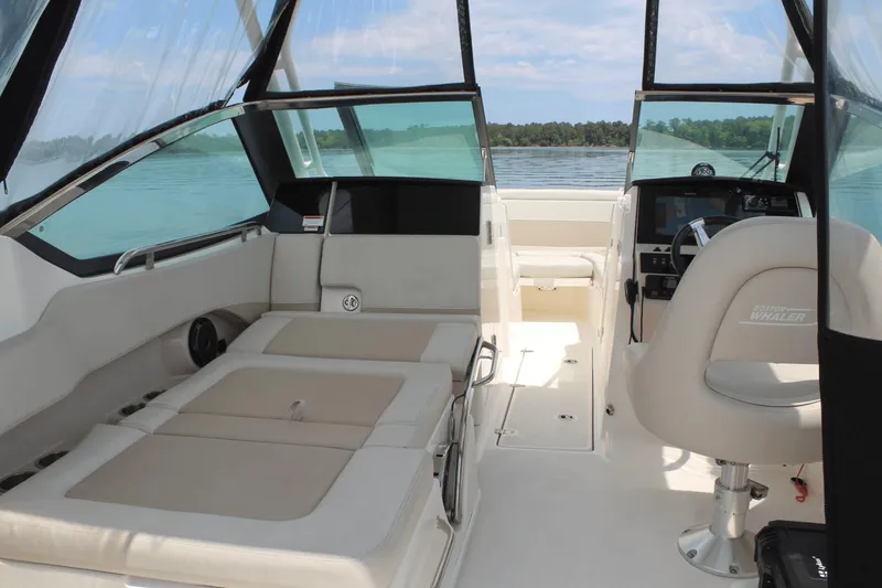 Slide: The Image of 2021 Boston Whaler 240 Vantage interior with seating and helm, overlooking serene water. - 45
