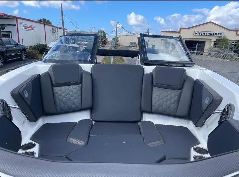 Slide: The Image of 2022 Scarab 255 ID boat interior with gray seating and cup holders, parked outdoors. - 7