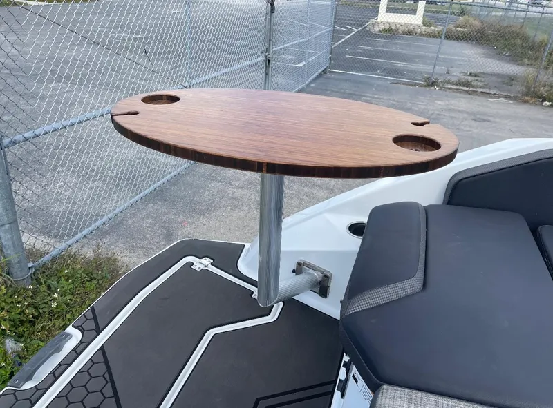 Slide: The Image of 2022 Scarab 255 ID boat with a wooden table and cushioned seating. - 8