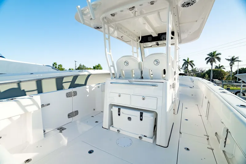 Slide: The Image of 2024 Edgewater 340CC boat interior with seating and storage, under clear blue sky. - 16