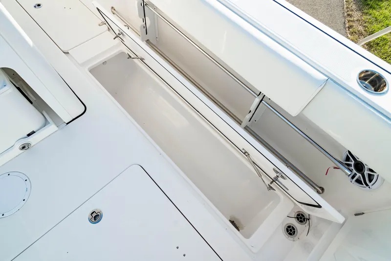 Slide: The Image of 2024 Edgewater 340CC boat deck with storage compartment and rod holders. - 18