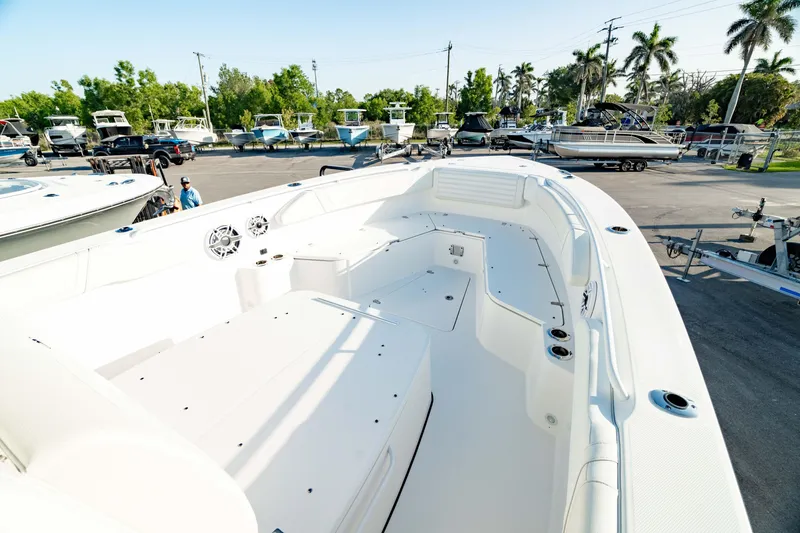 Slide: The Image of 2024 Edgewater 340CC boat interior, spacious deck, white seating, parked in marina. - 46