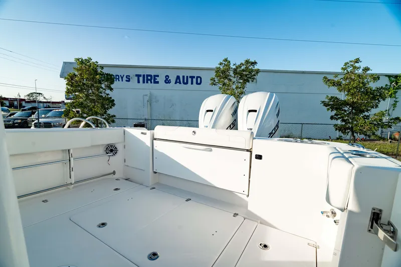 Slide: The Image of 2024 Edgewater 340CC boat deck with dual engines, parked near a tire and auto shop. - 7