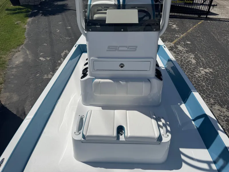 Slide: The Image of 2025 SCB R24 boat interior with white seating and console, parked on asphalt. - 12