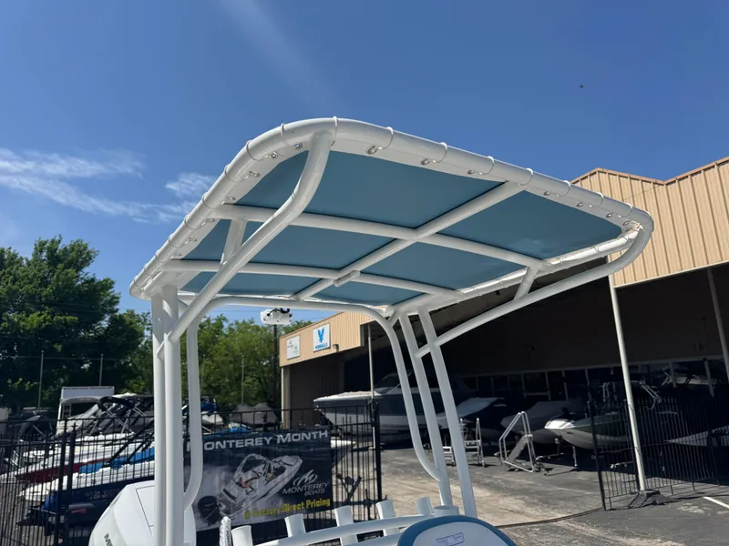 Slide: The Image of 2025 SCB R24 boat with blue canopy under clear sky at dealership. - 25