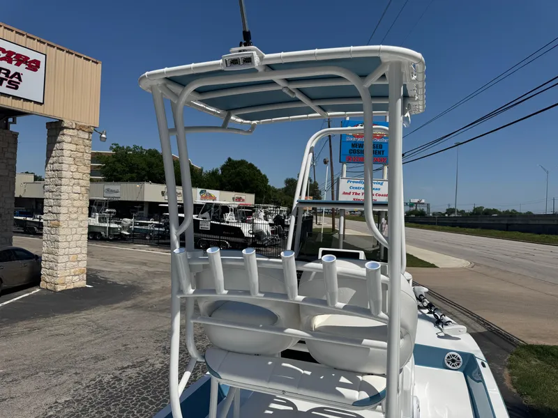 Slide: The Image of 2025 SCB R24 boat with rod holders and T-top, parked near a dealership. - 26