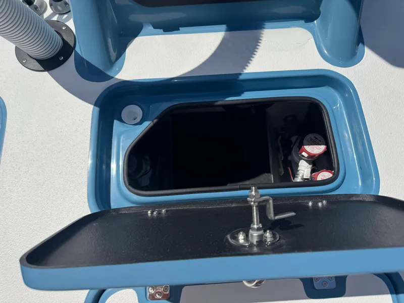 Slide: The Image of Open storage compartment on 2025 SCB R24 boat, featuring blue trim and secure latch. - 39