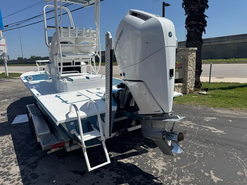 Slide: The Image of 2025 SCB R24 boat with outboard motor on a trailer, parked outdoors. - 4
