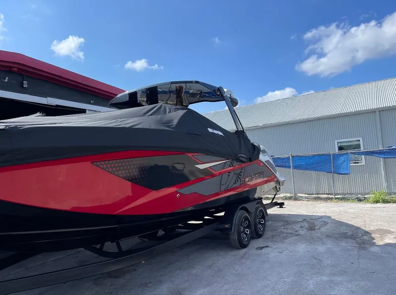 Slide: The Image of 2023 Scarab 285 ID boat with cover, parked outdoors under a clear blue sky. - 1