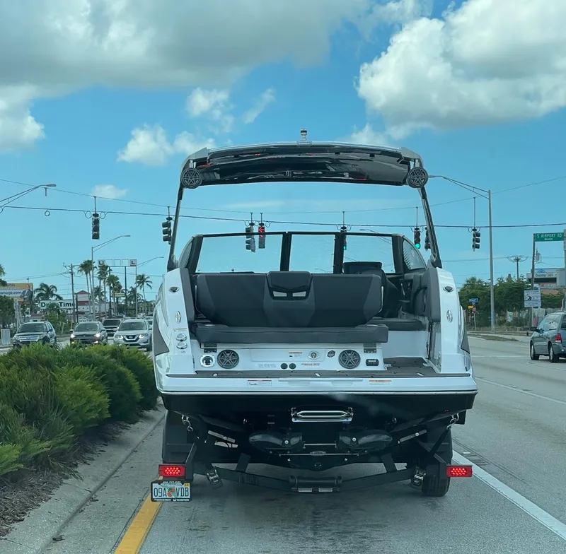 Slide: The Image of 2023 Scarab 285 ID boat on trailer, parked on a road under a clear blue sky. - 4