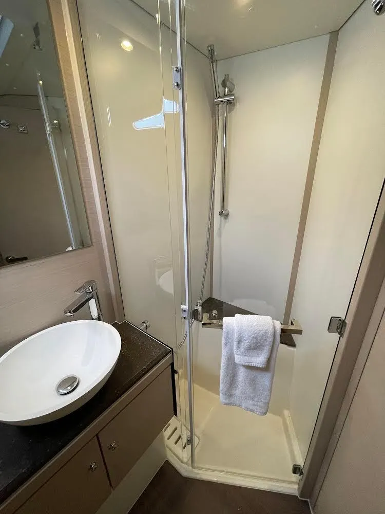 Slide: The Image of 2021 Jeanneau 54 sailboat with people on deck, cruising on calm waters under a clear sky. - 7