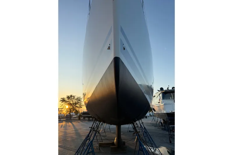 Slide: The Image of Jeanneau 54 yacht from 2021 on stands at sunset, showcasing sleek hull design. - 86