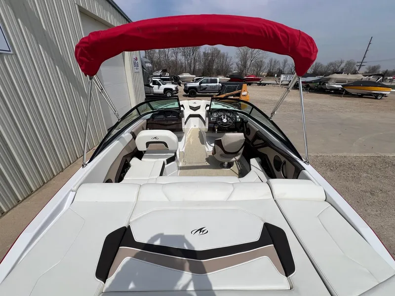 Slide: The Image of 2015 Monterey 218 Super Sport boat with red canopy and white seating, parked outdoors. - 14