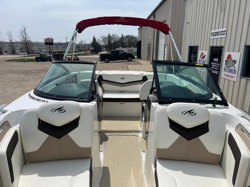 Slide: The Image of 2015 Monterey 218 Super Sport boat with red canopy, parked near a building. - 15