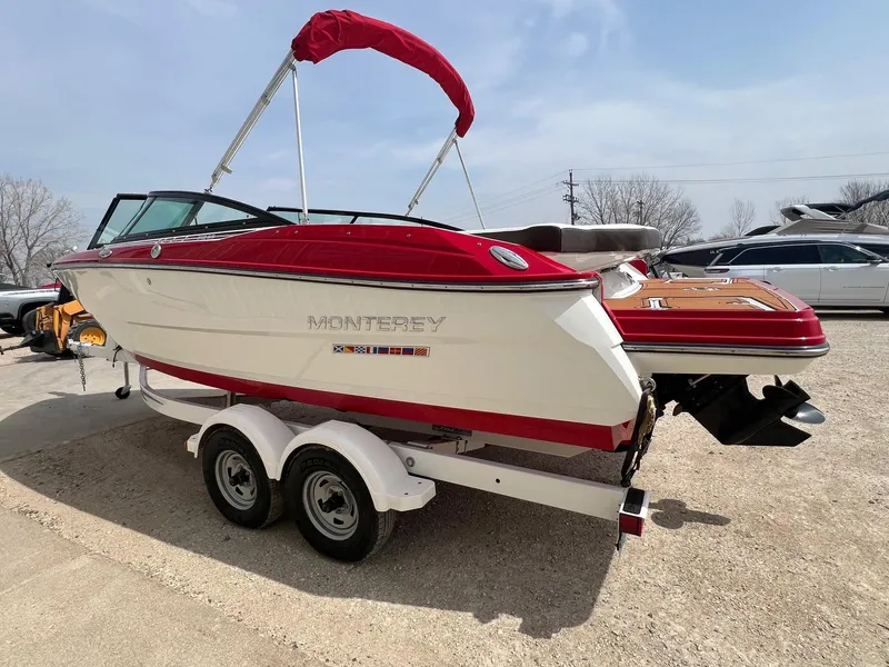 Slide: The Image of 2015 Monterey 218 Super Sport boat with red accents on a trailer, parked outdoors. - 8