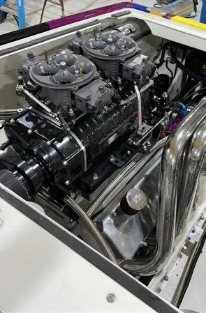 Slide: The Image of High-performance engine in a 1999 Skater 32B boat, featuring dual carburetors and polished components. - 12