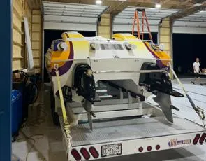 Slide: The Image of 1999 Skater 32B speedboat on trailer in garage, featuring vibrant yellow and purple accents. - 4