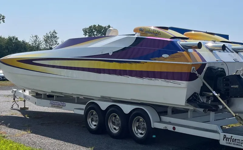 Slide: The Image of 1999 Skater 32B speedboat with colorful stripes on a trailer. - 7