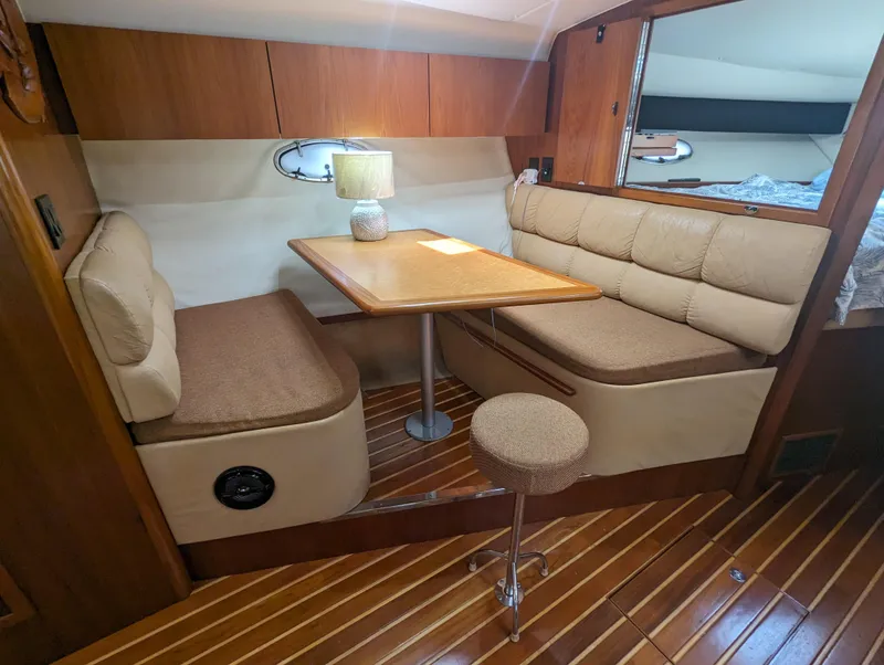 Slide: The Image of 2000 Tiara Yachts 3500 Express interior with cozy dining area and wooden flooring. - 11