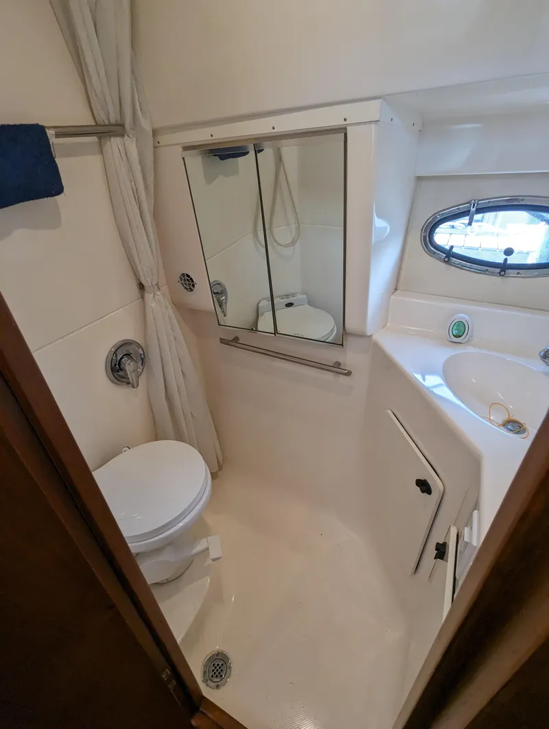 Slide: The Image of 2000 Tiara Yachts 3500 Express bathroom with toilet, mirror, and porthole window. - 21