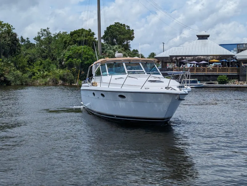 Slide: The Image of 2000 Tiara Yachts 3500 Express cruising on a calm river near a riverside restaurant. - 35