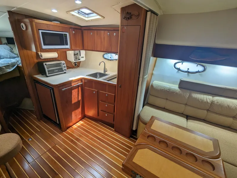 Slide: The Image of 2000 Tiara Yachts 3500 Express interior with kitchenette, sofa, and wooden flooring. - 5