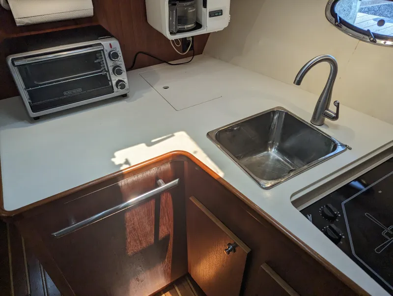 Slide: The Image of Compact yacht kitchen with sink, toaster oven, and wooden cabinetry in a 2000 Tiara Yachts 3500 Express. - 8
