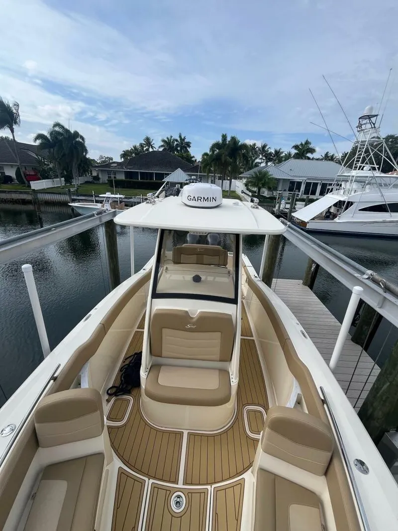 Slide: The Image of 2020 Scout 277LXF boat docked, featuring Garmin equipment, with elegant seating and scenic waterfront view. - 10
