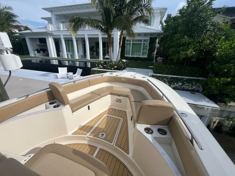 Slide: The Image of 2020 Scout 277LXF boat with luxurious seating, docked near a modern waterfront home. - 7