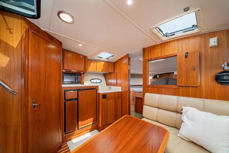 Slide: The Image of Interior of 2001 Tiara Yachts 3500 Open, featuring wood cabinetry and cozy seating. - 37