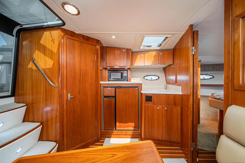 Slide: The Image of 2001 Tiara Yachts 3500 Open interior with wood cabinetry, kitchenette, and stairs. - 38