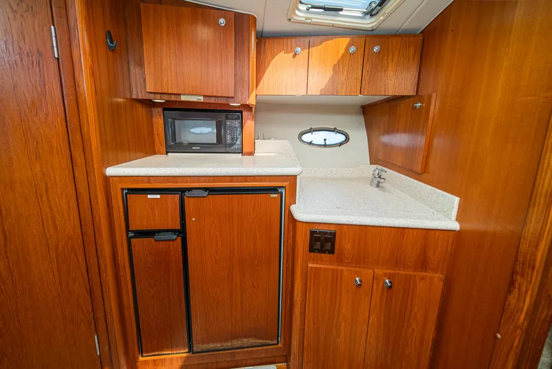 Slide: The Image of 2001 Tiara Yachts 3500 Open galley with wood cabinetry, microwave, and compact fridge. - 39