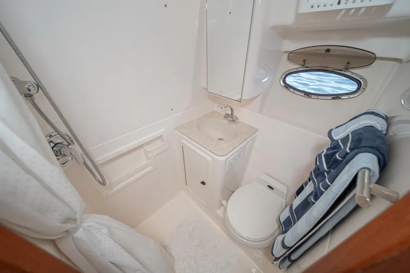 Slide: The Image of Compact bathroom in 2001 Tiara Yachts 3500 Open, featuring shower, sink, and porthole window. - 46