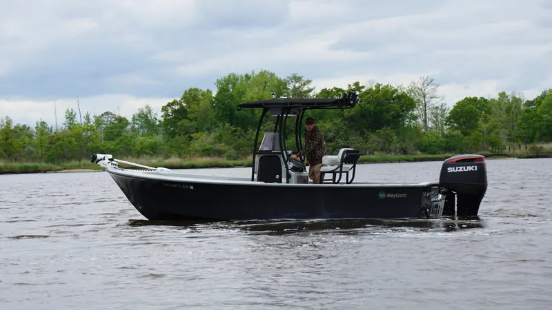 Slide: The Image of 2022 May-Craft 23 Cape Classic boat on a calm river with lush greenery. - 6