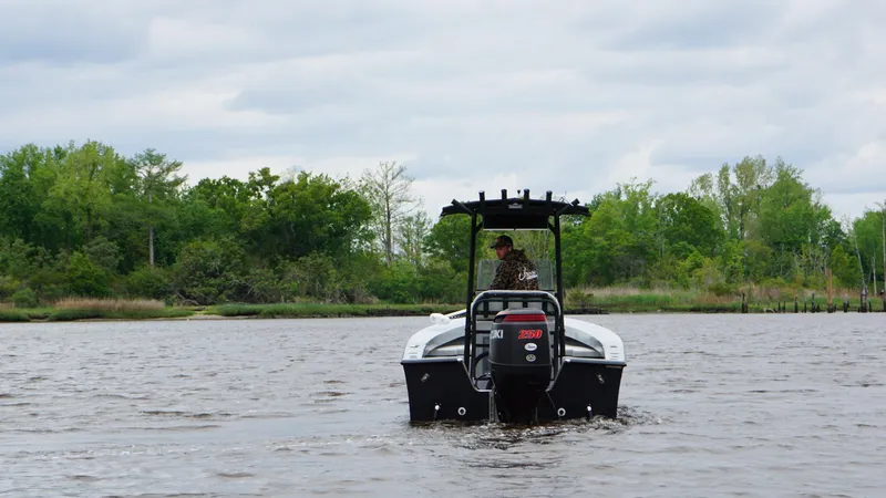 Slide: The Image of 2022 May-Craft 23 Cape Classic boat on a calm lake with lush green shoreline. - 7
