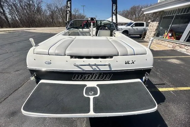 Slide: The Image of 2003 Malibu Wakesetter VLX boat, rear view, parked on pavement near a building. - 5