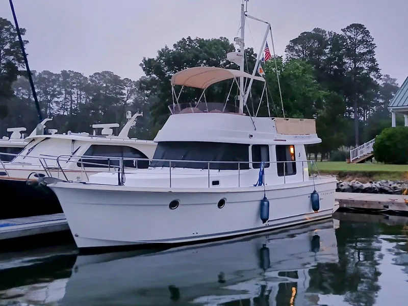 Slide: The Image of 2015 Beneteau Swift Trawler 34 docked at a marina, surrounded by trees. - 1
