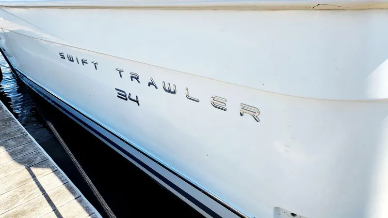 Slide: The Image of 2015 Beneteau Swift Trawler 34 boat side view with model name displayed. - 12