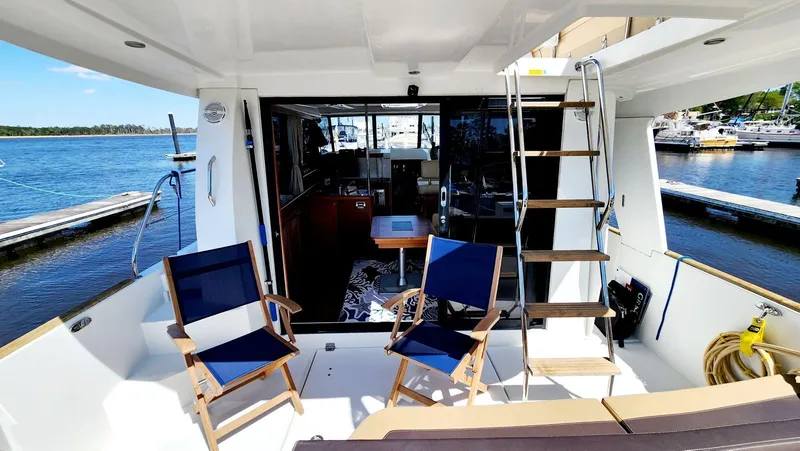 Slide: The Image of 2015 Beneteau Swift Trawler 34 deck with chairs, ladder, and marina view. - 13