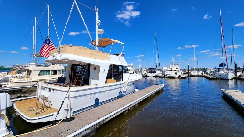 Slide: The Image of 2015 Beneteau Swift Trawler 34 docked at marina under clear blue sky. - 2