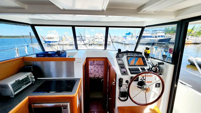 Slide: The Image of Interior view of 2015 Beneteau Swift Trawler 34 helm with navigation equipment and marina backdrop. - 28