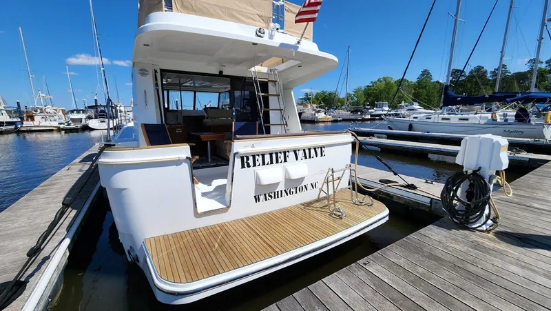 Slide: The Image of 2015 Beneteau Swift Trawler 34 docked, rear view, sunny marina setting. - 4