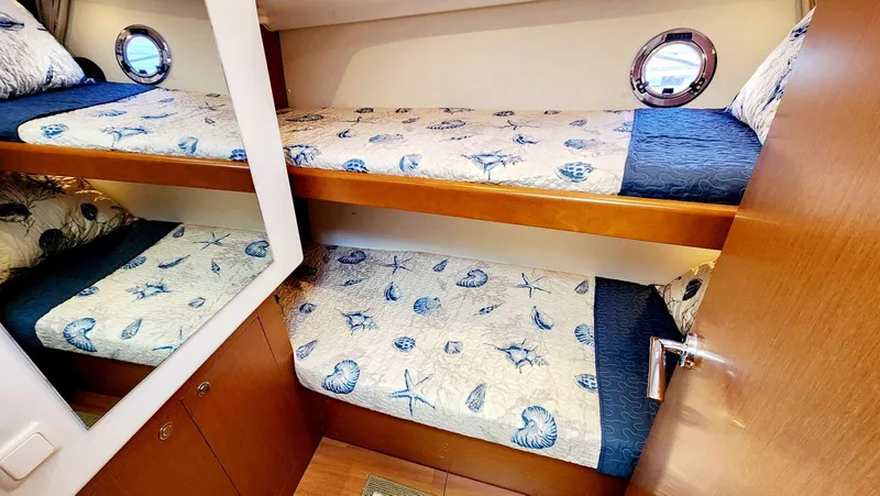 Slide: The Image of Bunk beds in 2015 Beneteau Swift Trawler 34 cabin with nautical-themed bedding. - 48
